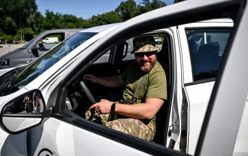 Militärpersonal in Tarnkleidung sitzt am Steuer eines weißen Autos, was die neuen Regeln der ukrainischen MVS für die Registrierung von humanitären Fahrzeugen illustriert – ein Fahrzeug pro Soldat