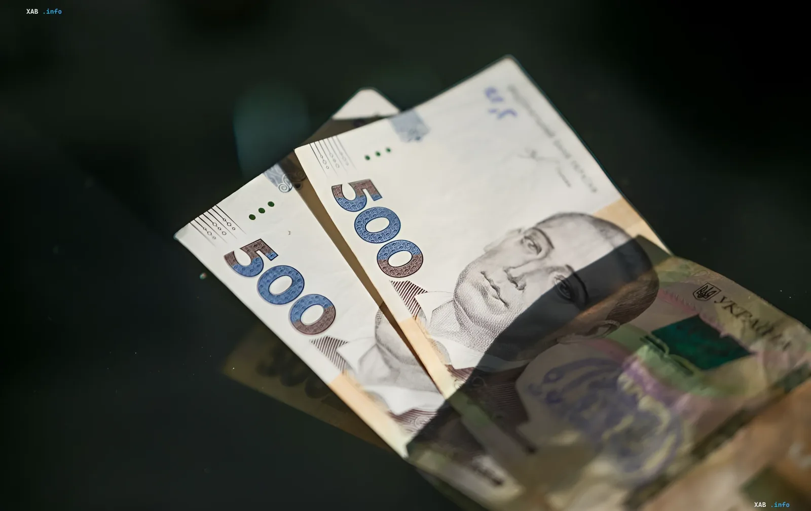 Украинские гривневые купюры номиналом 500 гривен на темном фоне, иллюстрирующие тему социальных выплат и пенсионного обеспечения в контексте требований МВФ