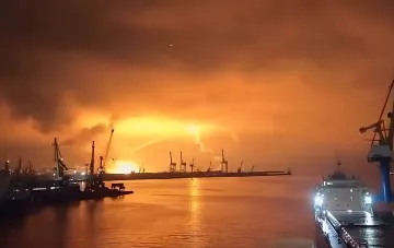 Пожар в порту Новороссийска ночью: огненный взрыв на фоне кранов и судов, иллюстрирующий удары дронов по экспорту зерна и нефти