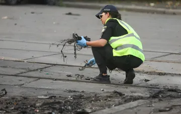 Полицейский в защитном жилете и перчатках осматривает обломки дрона после обезвреживания взрывчатки в Одессе
