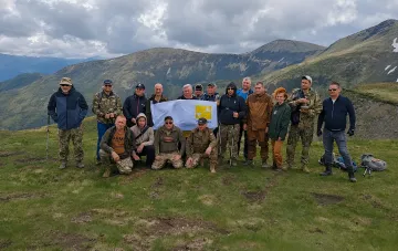 Группа ветеранов Интерпайп с флагом компании на фоне гор Карпат во время восстановительного похода