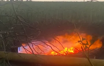 Fire on a gas pipeline in Odesa after drone strikes: bright flames engulf the ground, charred branches and smoke visible