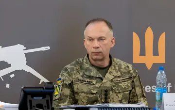 Генерал-полковник Александр Сырский в военной форме на пресс-конференции, на фоне — герб Украины и символ Вооруженных сил; ключевая фигура в новости об отставке главнокомандующего