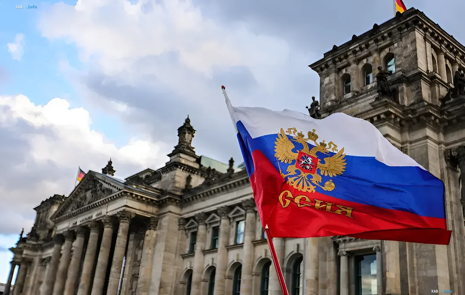 Флаг России с двуглавым орлом развевается перед Рейхстагом в Берлине, символизируя политическую связь между Берлинской партией и Москвой на фоне отдаления Европы