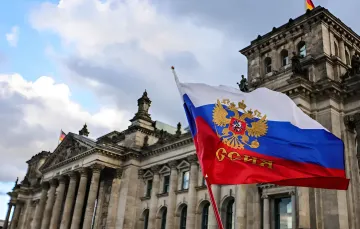 Флаг России с двуглавым орлом развевается перед Рейхстагом в Берлине, символизируя политическую связь между Берлинской партией и Москвой на фоне отдаления Европы