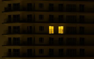 Mehrfamilienhaus nachts mit einem beleuchteten Fenster, das den Stromausfall in Tschernihiw nach dem Angriff symbolisiert