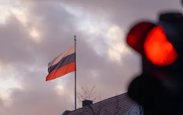 Флаг России на фоне заката и красного светофора, символизирующего остановку или предупреждение в контексте 21-го пакета санкций ЕС