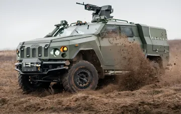 Armored MaxxPro vehicle with machine gun turret navigating mud, symbolizing logistics survival on the last mile