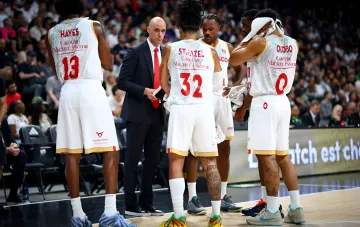 Monaco basketball coach conducting a tactical discussion with players during a game break