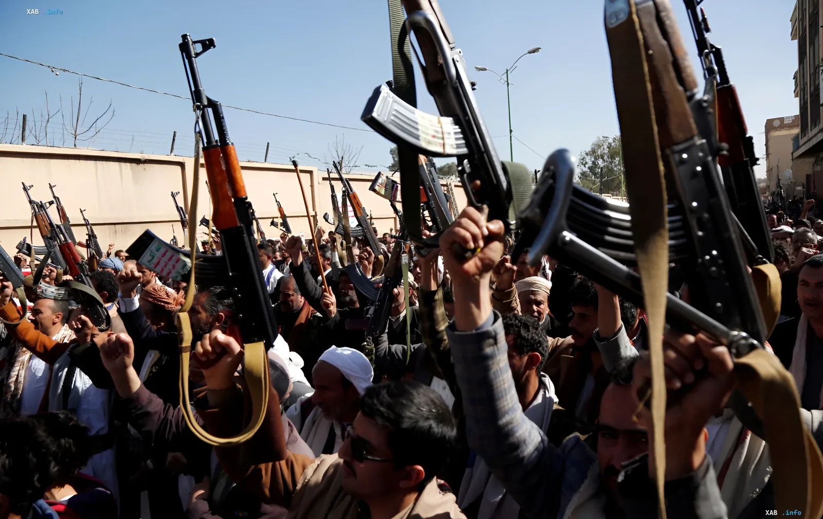 Men with rifles at a rally in the Middle East, symbolizing conflict escalation affecting oil prices