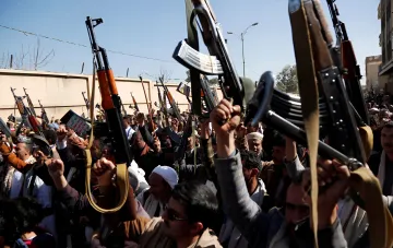 Men with rifles at a rally in the Middle East, symbolizing conflict escalation affecting oil prices