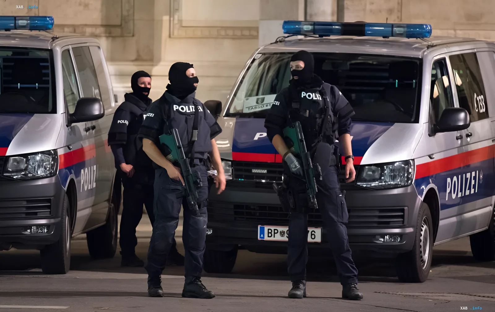 Вооруженные сотрудники австрийской полиции (Polizei) в масках и бронежилетах стоят у полицейских фургонов перед зданием, где находится полицейский участок в доме Гитлера, символизируя превращение нацистского символа в барьер для радикалов.