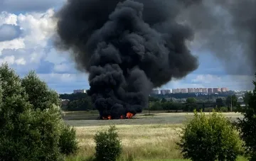 Large fire and thick black smoke from a crashed Su-57 fighter jet in a field in the Moscow region