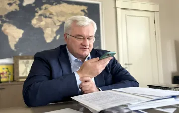 Andriy Sybiga, Ukraine's Minister of Infrastructure, examines data on his smartphone in the office, discussing Russia's attacks on merchant ships in the Black Sea.