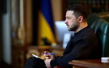 Ukrainischer Präsident Wolodymyr Selenskyj in seinem Büro mit der ukrainischen Flagge im Hintergrund, diskutiert das Abkommen zur gemeinsamen Produktion von Patriot-Raketen mit Raytheon