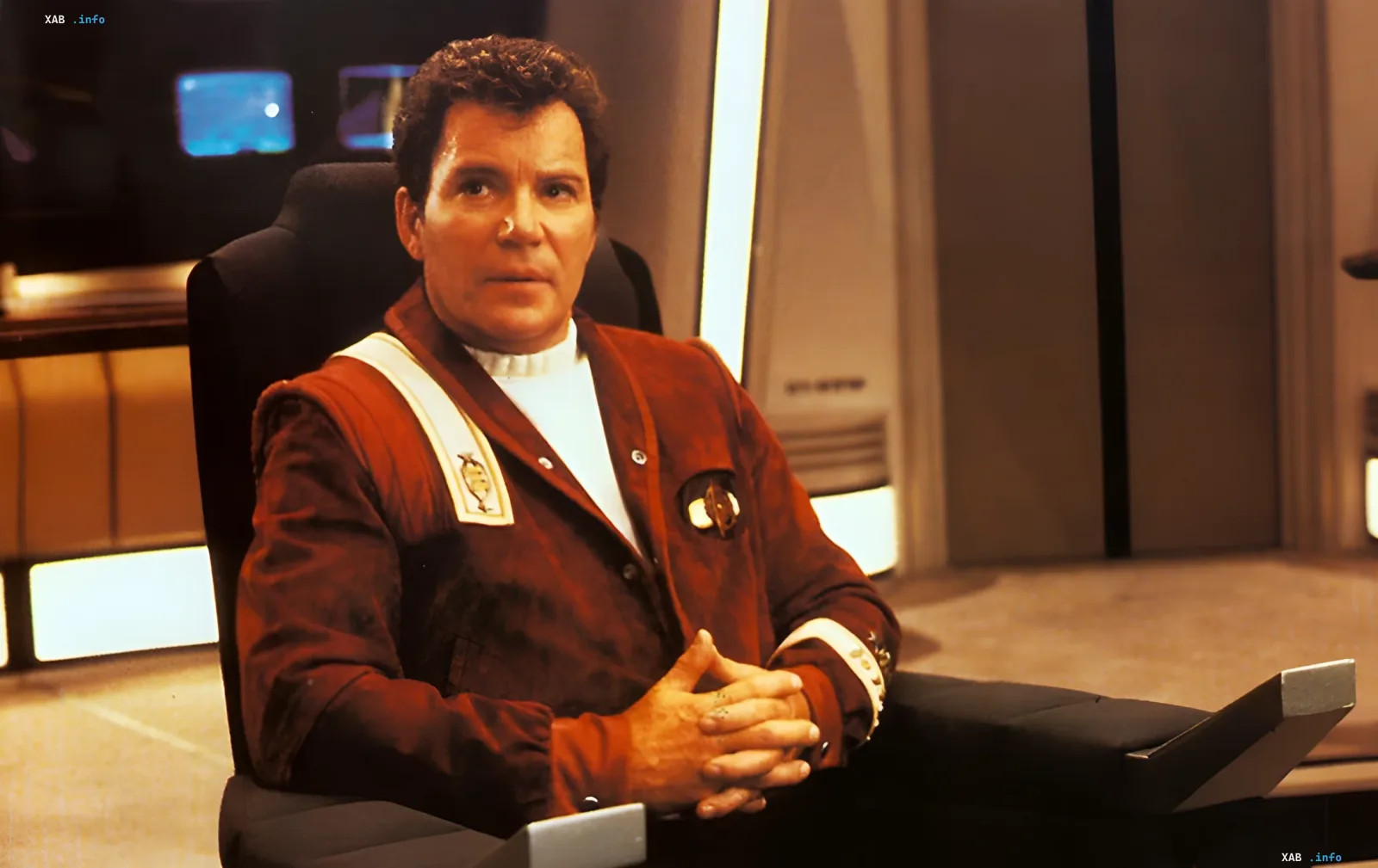 William Shatner als Captain James T. Kirk aus Star Trek, sitzend im Captain-Stuhl — Symbol seiner legendären Rolle und persönlichen Überwindung von Krebs