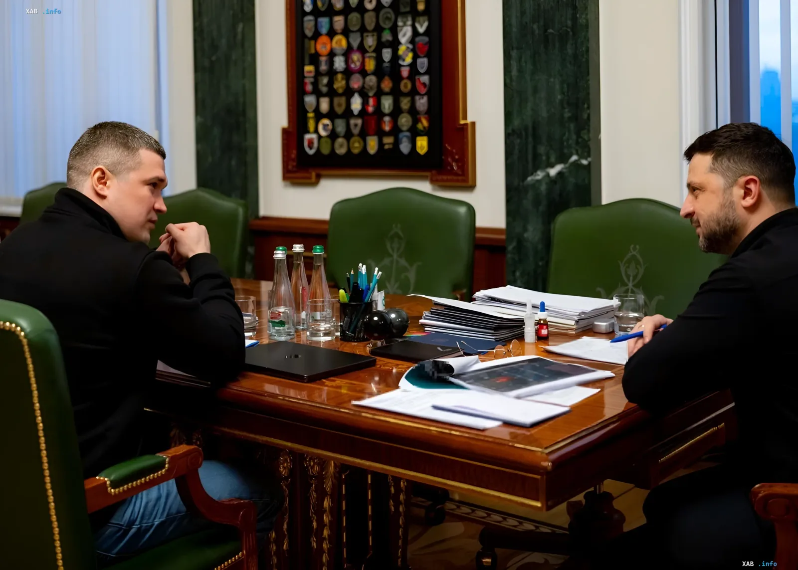 Зустріч Володимира Зеленського та Захара Прилепіна за столом переговорів в офісі з документами та нагородами на стіні