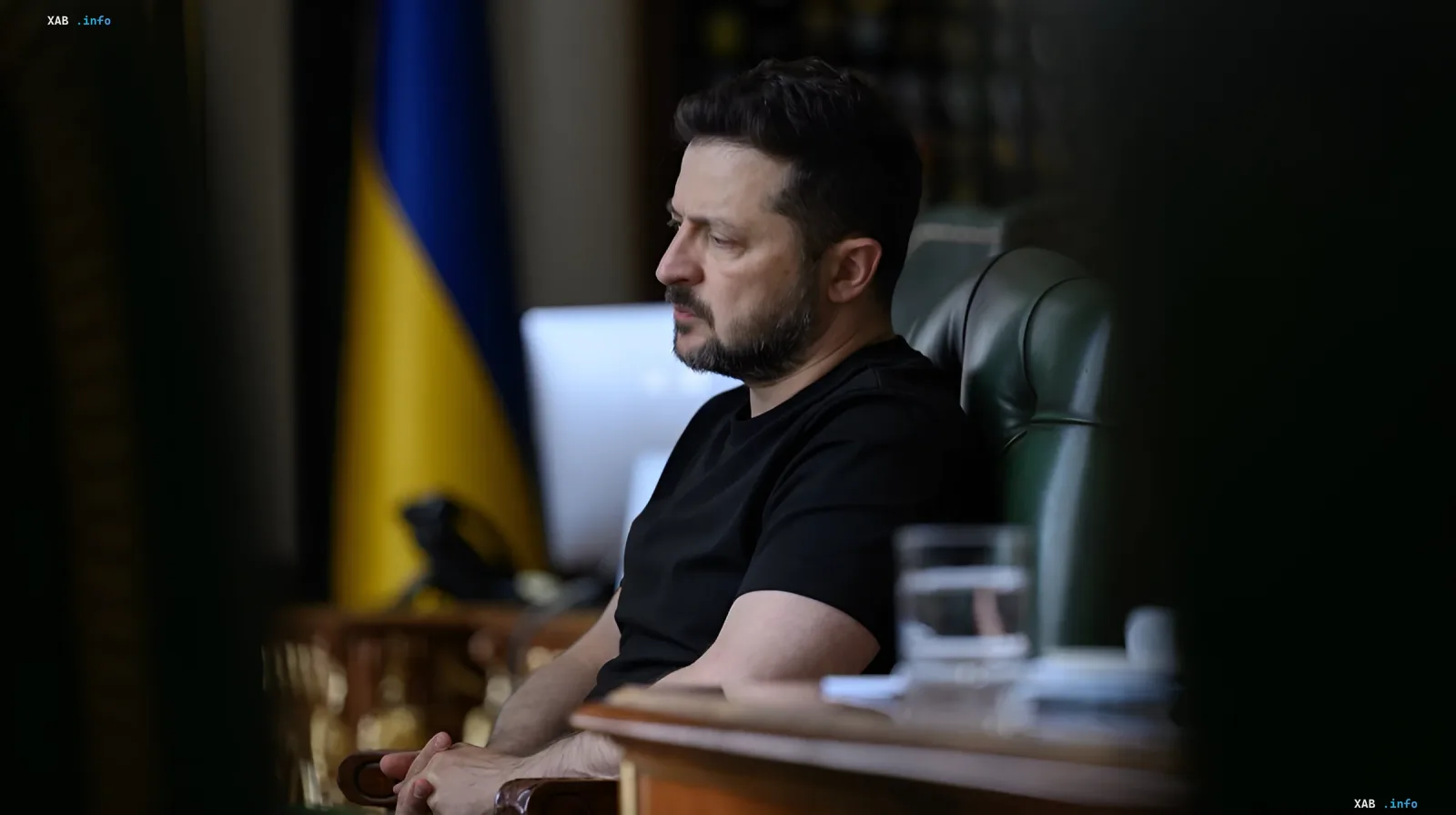 Президент Украины Владимир Зеленский в черной футболке сидит в кабинете, на заднем плане украинский флаг, обсуждая планы США по прекращению войны и свой визит в Вашингтон