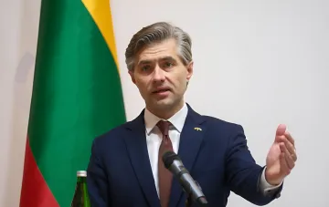 Габриэлюс Бландис выступает с речью на фоне флага Литвы, предупреждая об опасности для единства ЕС из-за санкций с уступками