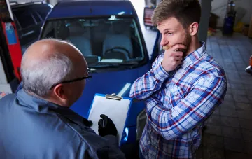 Механік обговорює з власником іномарки проблеми ремонту в перевантаженому автосервісі