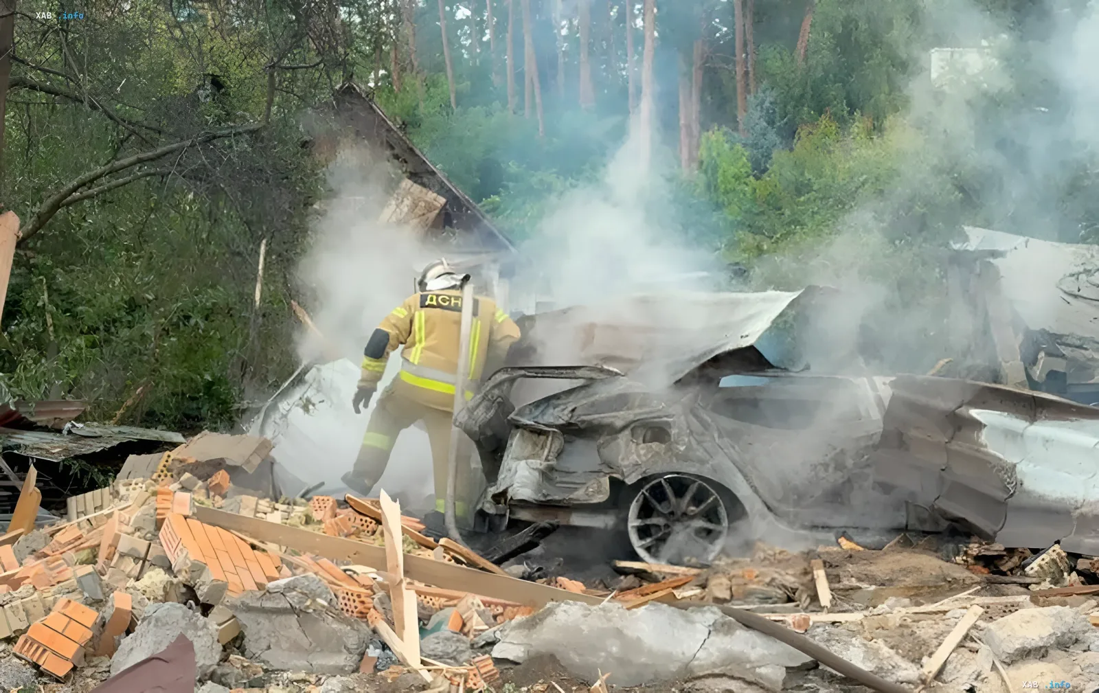 Feuerwehrmann löscht brennendes Auto unter Trümmern eines zerstörten Gebäudes nach Ballistik-Raketen-Anschlag auf privaten Schießstand in Kiew