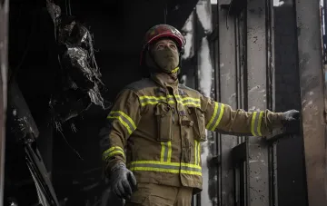 Пожарный в защитной экипировке осматривает разрушенное здание после атаки на Одессу
