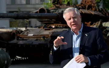 Senator Lindsey Graham mit Dokumenten vor einem zerstörten Panzer, diskutiert Sanktionen gegen Russland