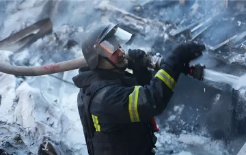 Пожарный тушит пожар на железнодорожном составе после атаки в Запорожье