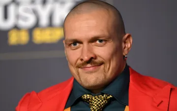 Александр Усик в красном пиджаке и желтом галстуке на фоне логотипа USYK — отказался от президентской гонки, заявив, что набрал бы больше голосов