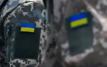 Ukrainian soldiers with flag patches — symbol of defenders whose rights to combat pay and indexation are often violated