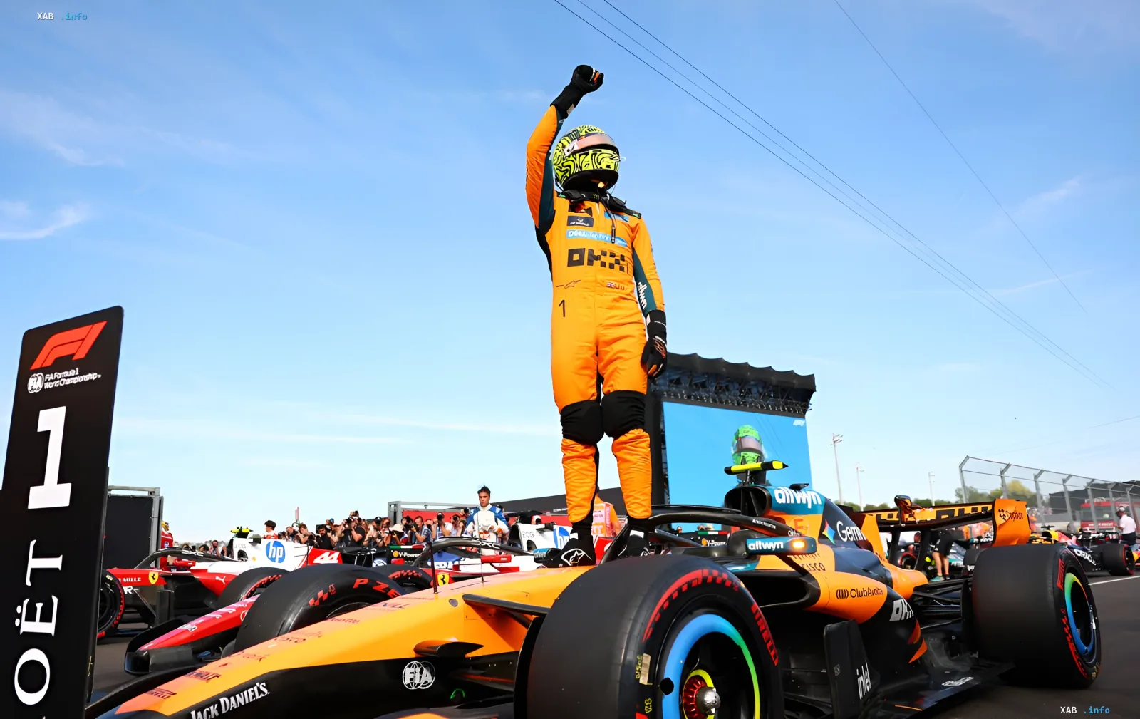 Ландо Норрис празднует победу на Гран-При Венгрии, стоя на болиде McLaren с поднятой рукой