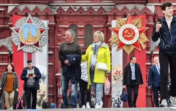 Люди проходят мимо советских медалей на Красной площади в Москве, что символизирует исторический контекст напряжённых отношений между Россией и Литвой