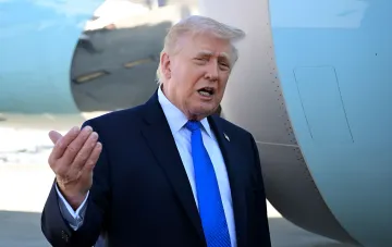 Дональд Трамп в костюме и синем галстуке говорит на фоне самолета, обсуждая дипломатические переговоры с Ираном и возможные военные действия