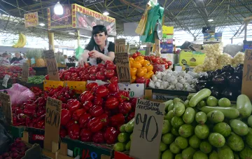 Овощная лавка на украинском рынке: красные перцы, баклажаны и кабачки с ценниками в гривнах, иллюстрирующая динамику цен на продукты