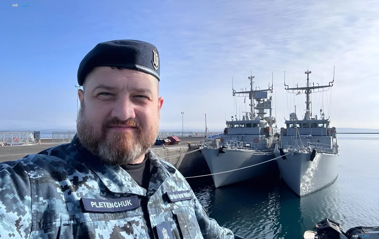 Украинский моряк в камуфляжной форме на фоне военных кораблей у причала, символизируя готовность ВМС Украины к ответу на угрозы Ирана после инцидента на Каспии