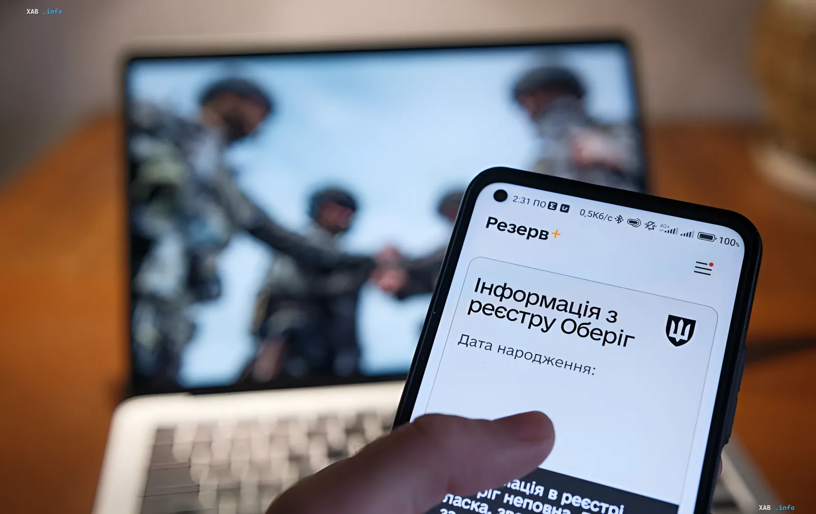 Smartphone mit der App 'Rezerv+' auf dem Bildschirm, die Daten aus dem Oberyh-Register anzeigt, im Hintergrund verschwommen Soldaten