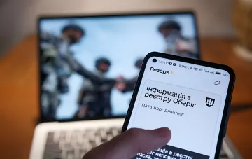 Smartphone mit der App 'Rezerv+' auf dem Bildschirm, die Daten aus dem Oberyh-Register anzeigt, im Hintergrund verschwommen Soldaten