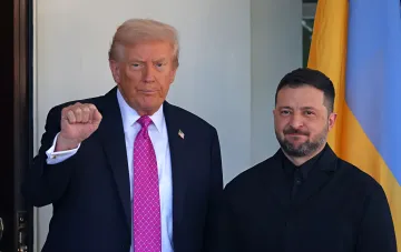 Дональд Трамп и Владимир Зеленский стоят рядом, Трамп делает жест кулаком, на фоне флаг Украины