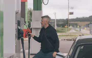 Ein Mann tankt ein Auto an einer Tankstelle, was das Thema des Schutzes von Tankstellen an der Front in der Ukraine illustriert