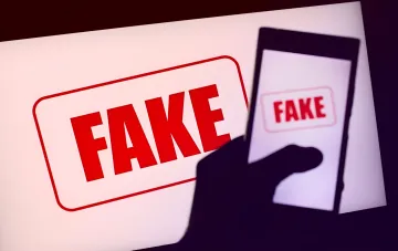 Изображение с надписью 'FAKE' на экране смартфона и фоне, символизирующее фейковые новости о наборе в Силы беспилотных систем Украины