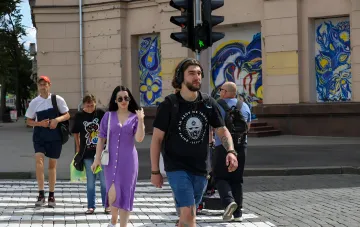 Пешеходы переходят дорогу по «зебре» на фоне светофора с зеленым сигналом — иллюстрация к статье о новых правилах остановки водителей перед пешеходным переходом