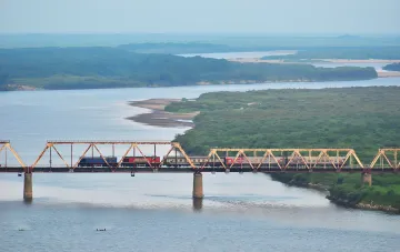 Поїзд перетинає залізничний міст через річку, символізуючи прихований логістичний коридор між Росією та КНДР