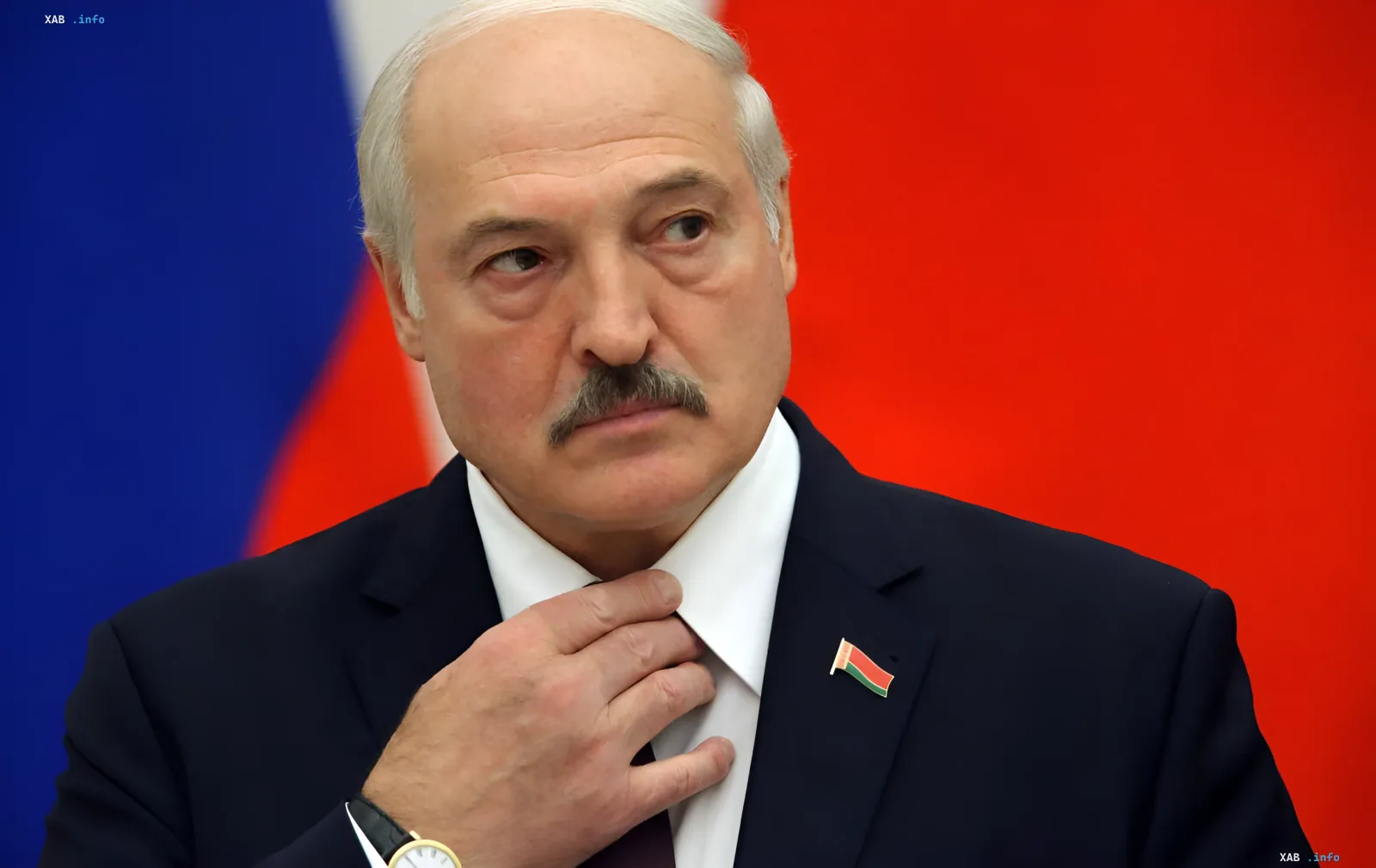 Александр Лукашенко в официальном костюме с флагом Беларуси на лацкане, на фоне флагов России и Беларуси — в контексте возможного уголовного дела со стороны Украины
