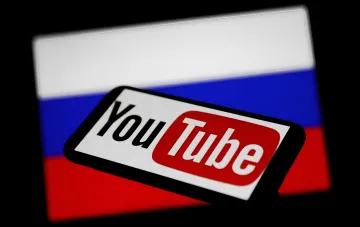 YouTube-Logo vor russischer Flagge, das die Blockierung von Propagandakanälen in der Ukraine symbolisiert