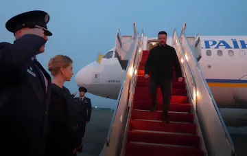 Президент Украины Владимир Зеленский спускается по трапу самолета в США, где его встречают официальные лица; визит связан с обсуждением антибаллистической защиты и встречей с Дональдом Трампом на фоне похорон Линкольна Грэма