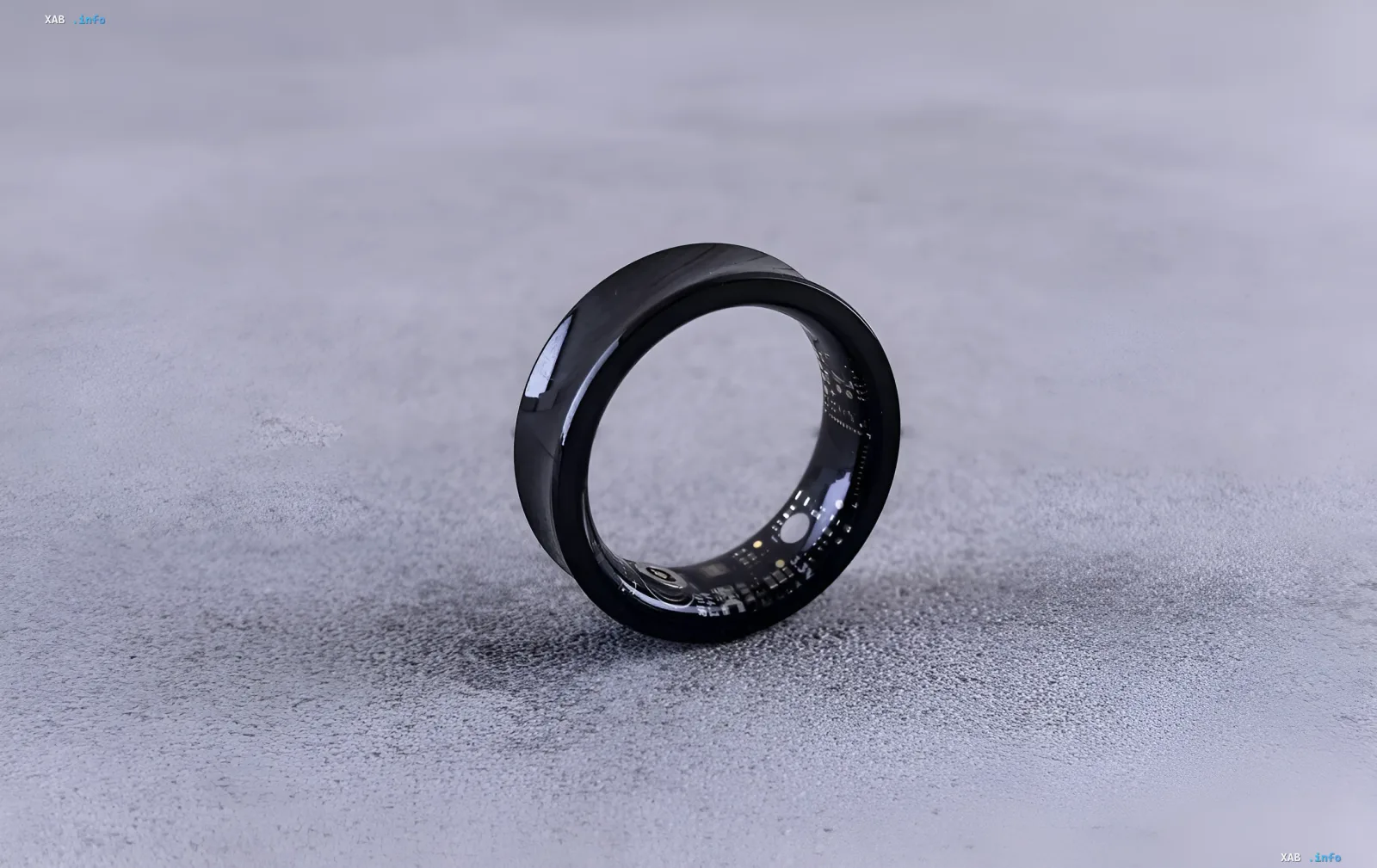 Черное умное кольцо Apple Ring с видимой внутренней электроникой на сером фоне, иллюстрирующее новый патент на универсальный пульт для экосистемы