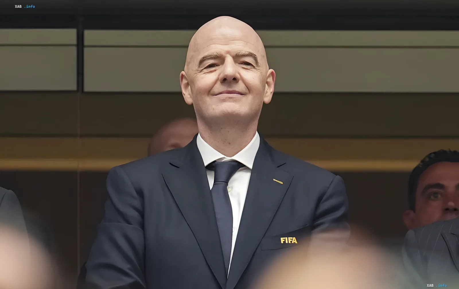 Жан-Мишель Инфантино в костюме с логотипом FIFA, символизирующий его амбициозный план по привлечению миллиардных инвестиций в футбол, который вызывает споры в мировом спорте