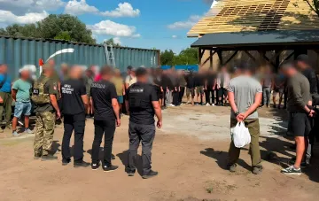 Задержание людей, подозреваемых в рабстве, сотрудниками полиции и военной полиции на фоне строящегося дома под Одессой