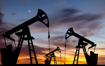 Силуэты нефтяных вышек на фоне заката: рост цен на нефть из-за ударов США и Саудовской Аравии по Ираку