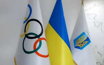 Флаги Олимпийского движения, Украины и Национального олимпийского комитета Украины рядом — символ спора между НОК и МОК по делу о восстановлении прав ОКР